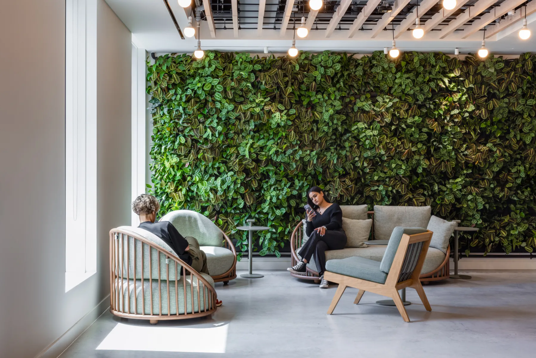 Two people sitting in chairs in front of a green wall