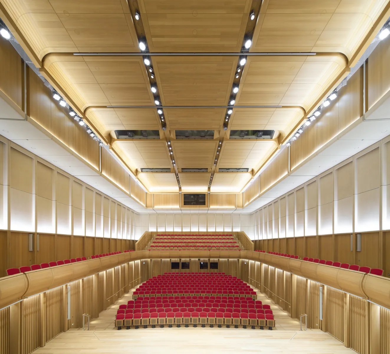 An internal photograph of the performance space, with red seats and wooden finishes