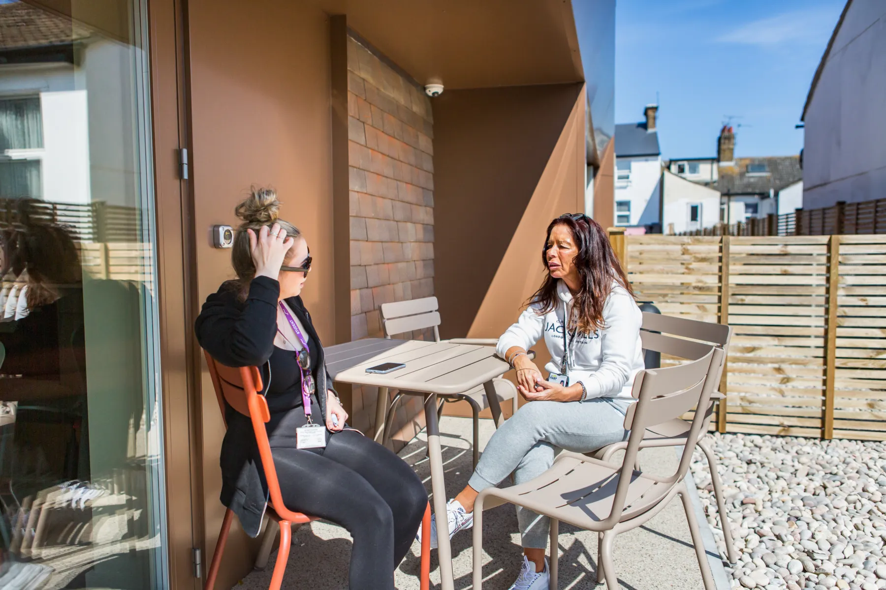 People sat chatting on terrace area in sunshine.