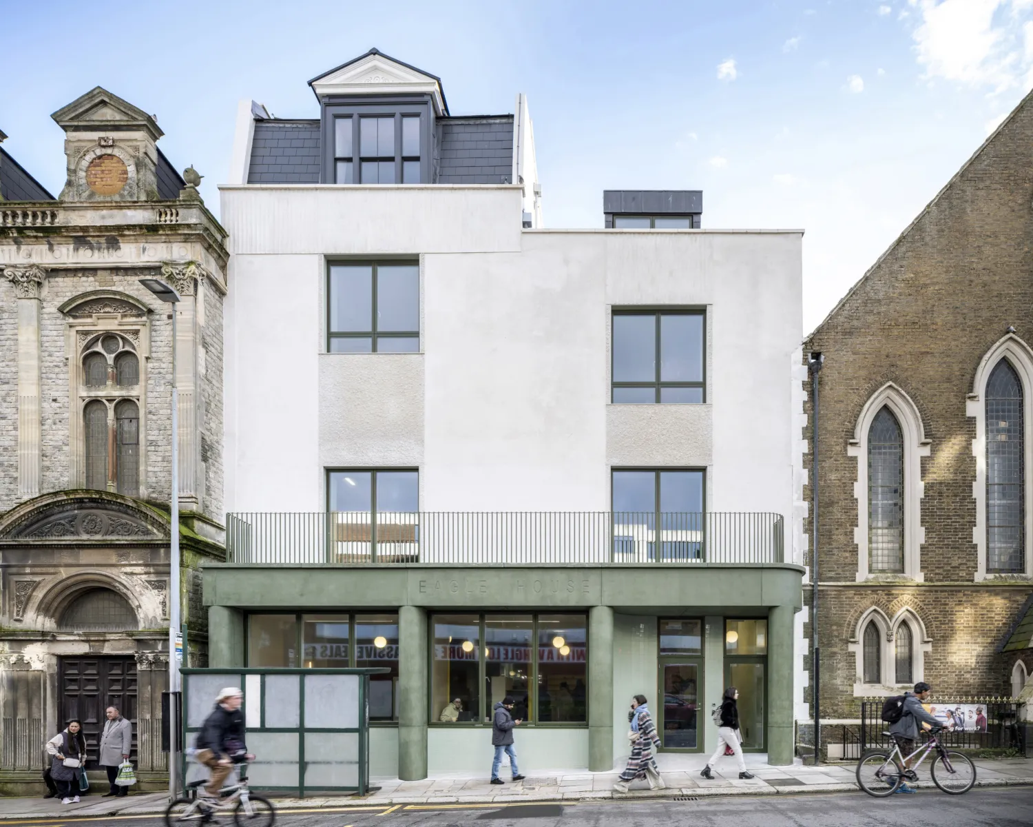 Contemporary mixed-use building frontage between two historic buildings.