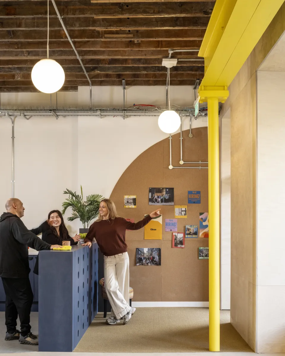 Reception area with bright yellow columns and people in conversation.