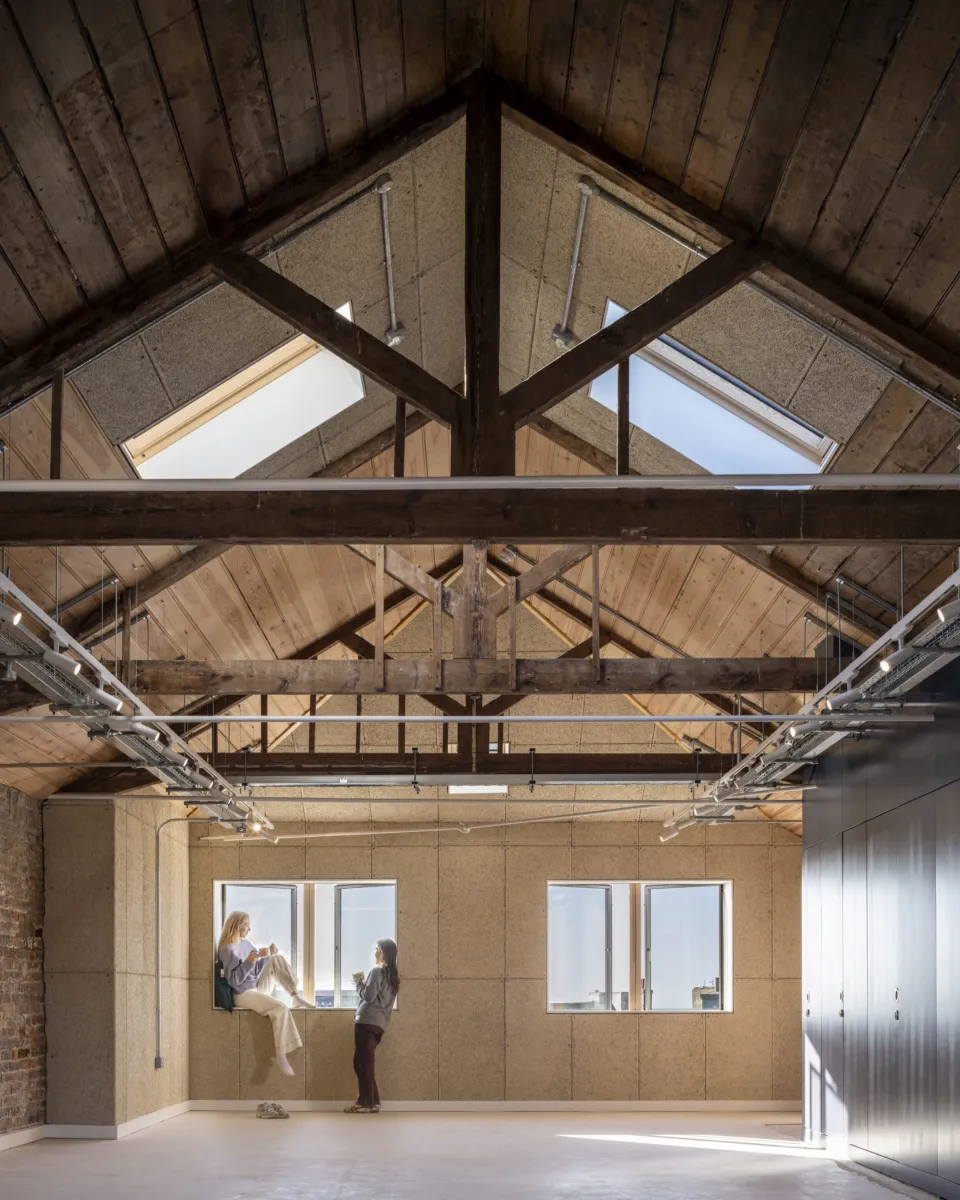 Open-plan workspace with exposed timber roof structure and rooflights.