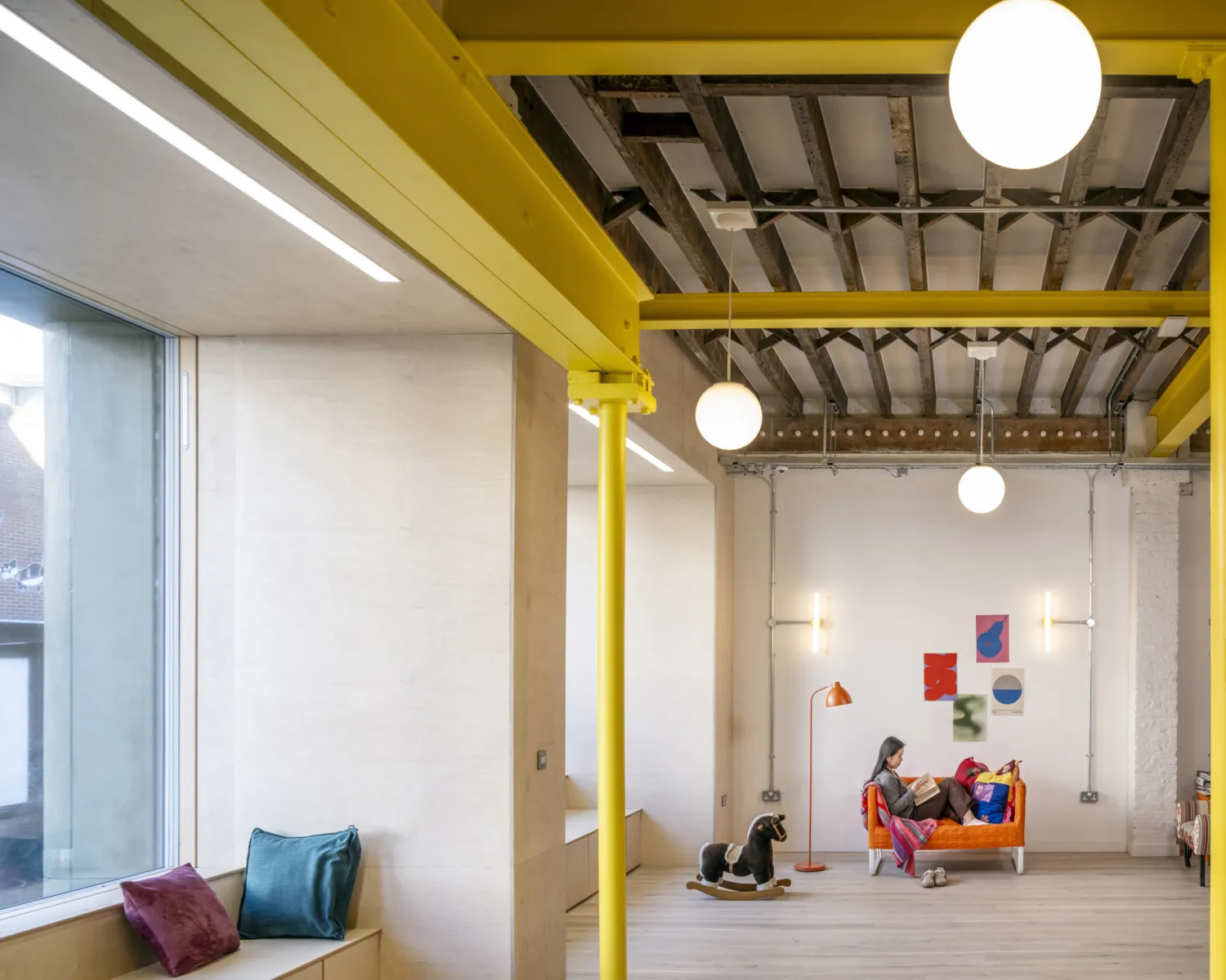 Lounge area with colourful furnishings and exposed structure.