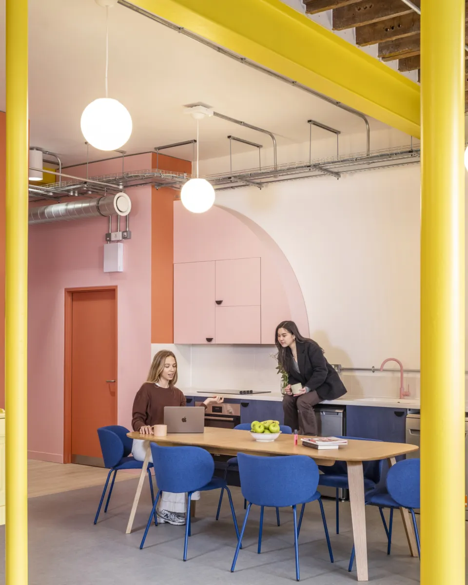 Bright workspace with large windows, seating and communal tables.