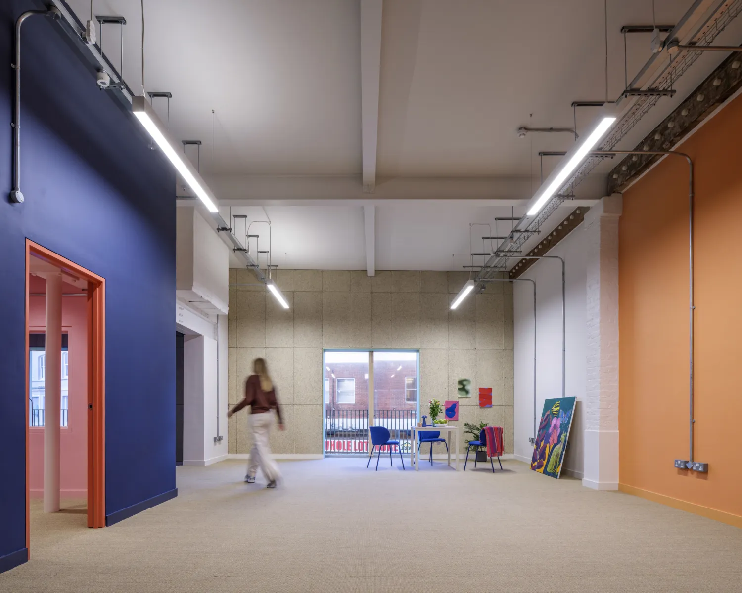 Collaborative workspace with communal table beneath exposed yellow steel beams.