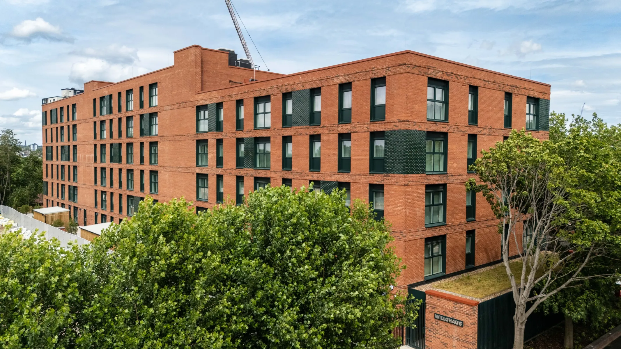 Exterior view of Willohaus, a red-brick residential building surrounded by mature trees.