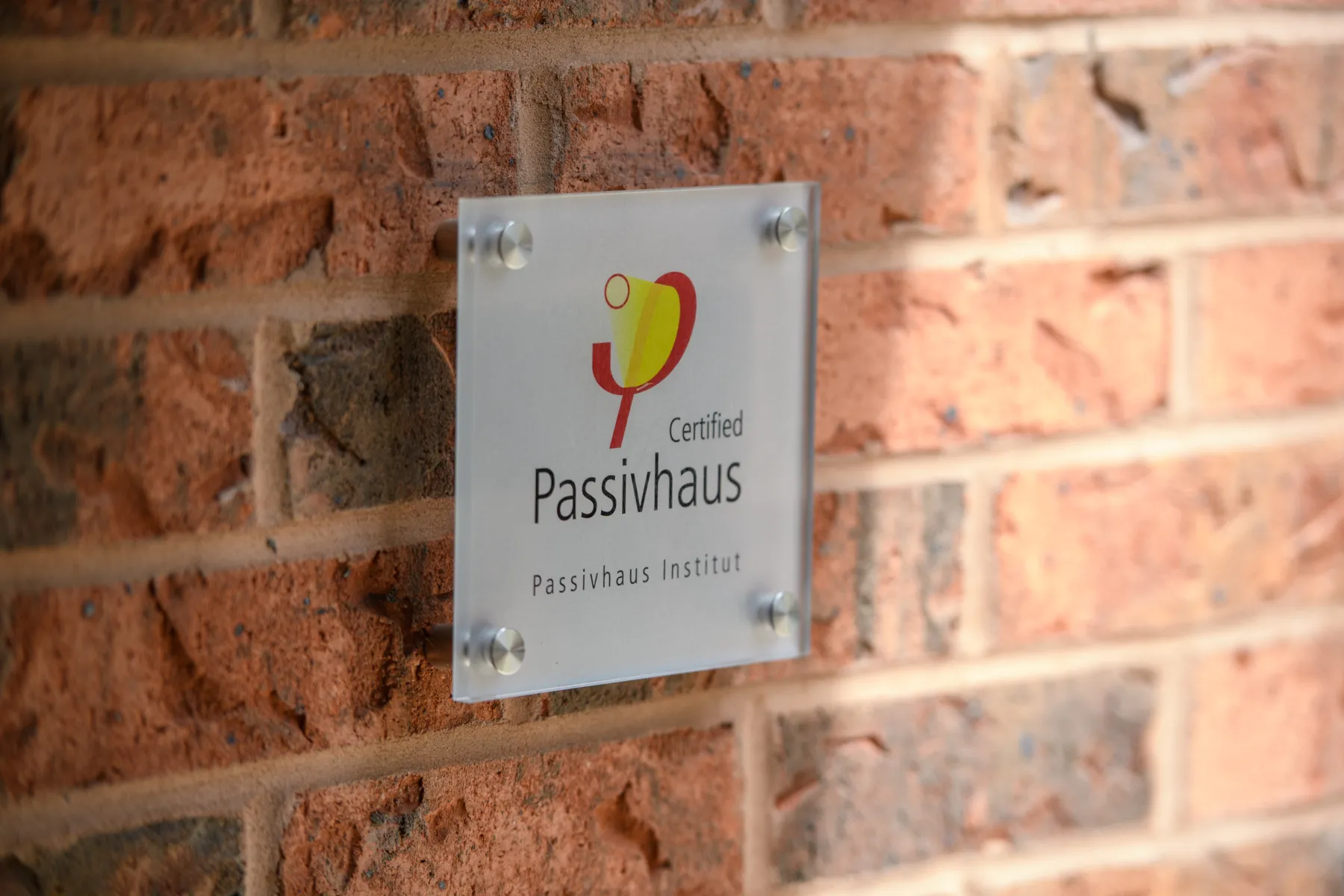 Willohaus building sign in brushed metal lettering fixed to a red-brick wall.