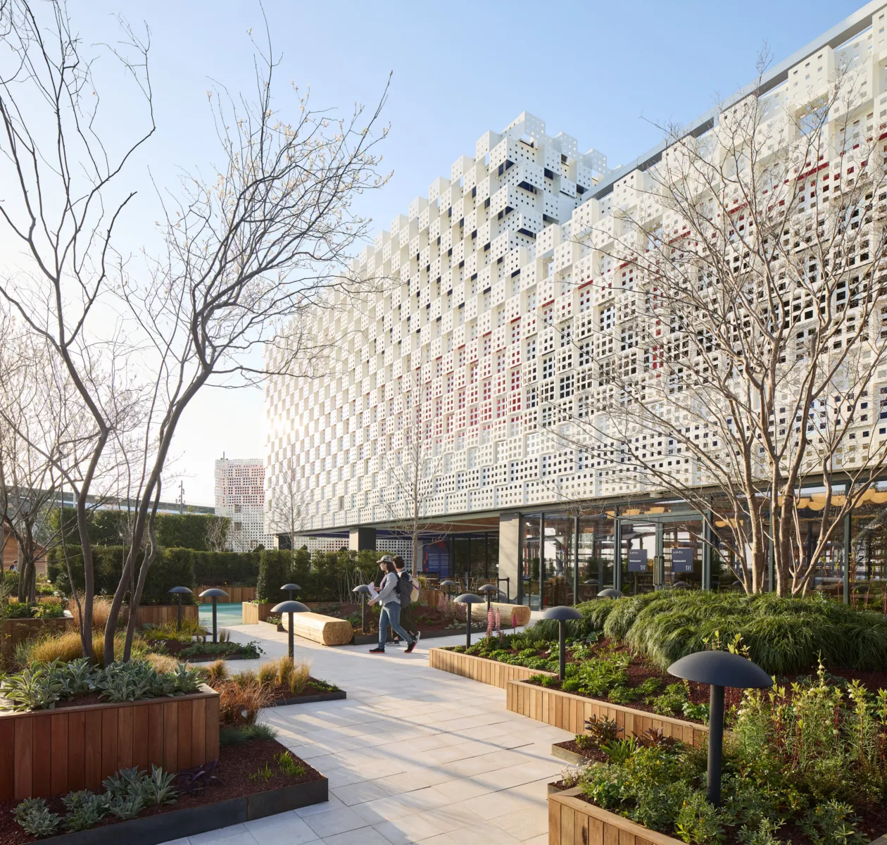 The image shows a large modern building with a facade that has tiny holes in it, with the British flag underneath.