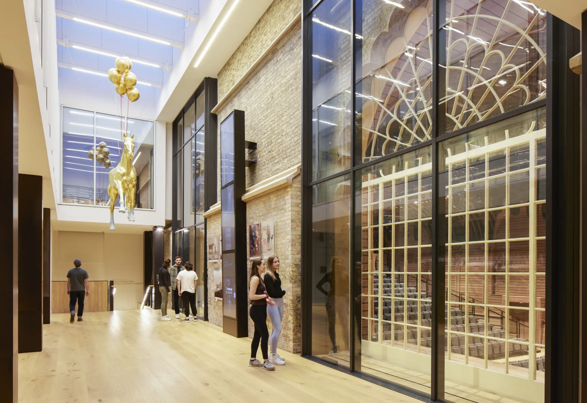A group of people walking through a spacious building with transparent glass walls
