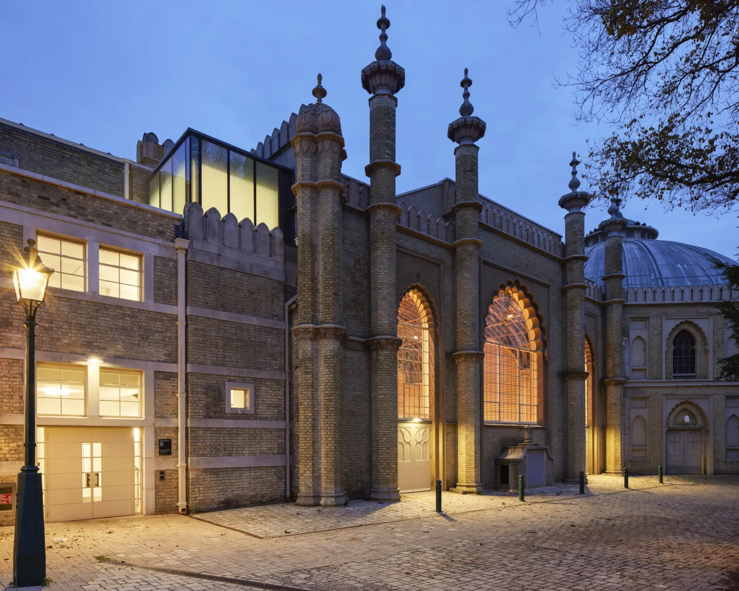 A building featuring clock tower and lit pathway
