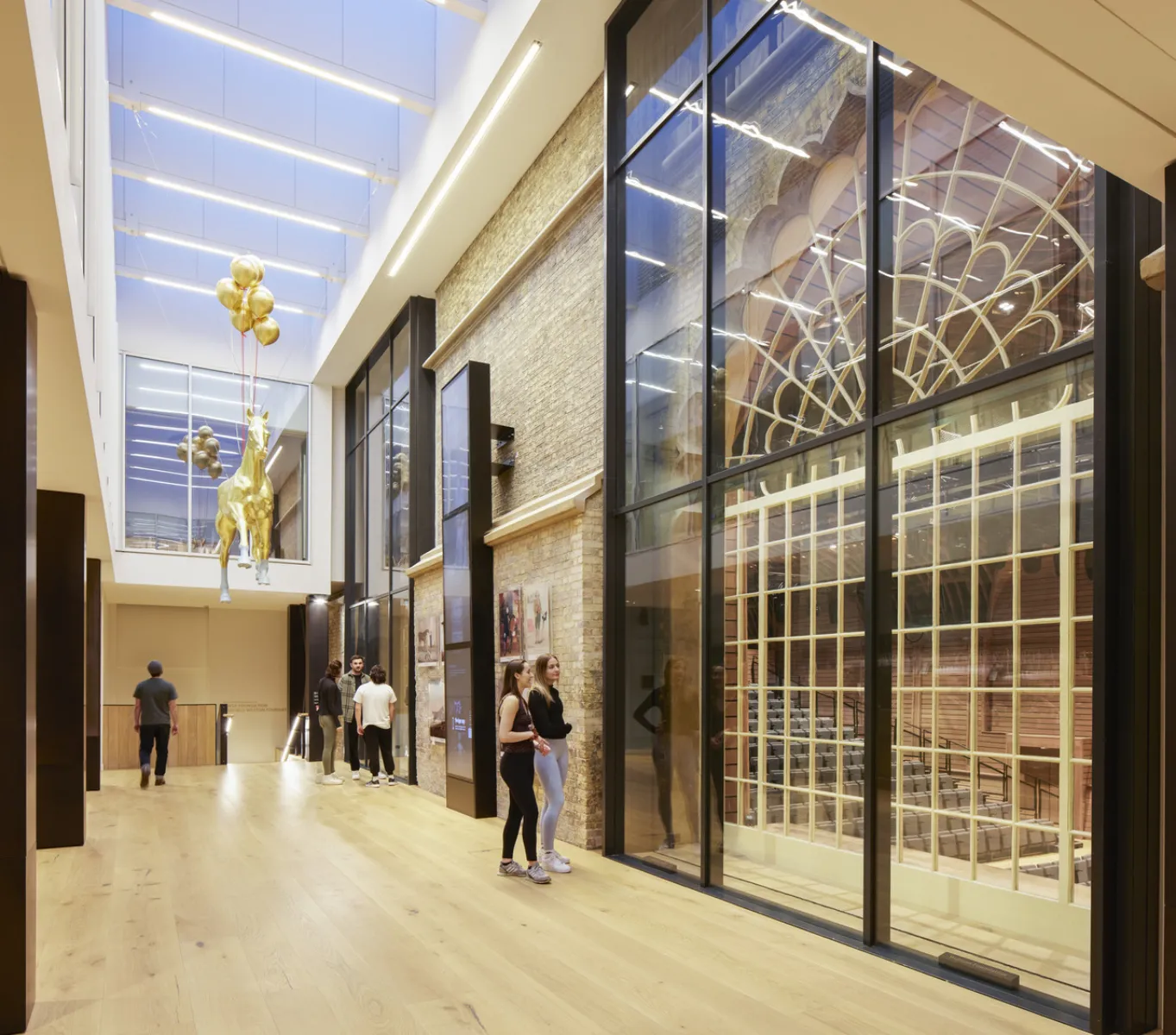 A group of people walking through a spacious building with transparent glass walls