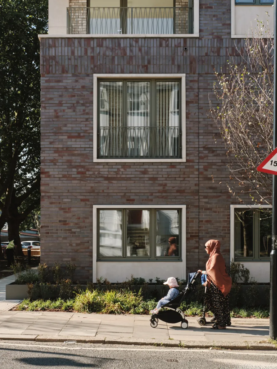 woman pushing a stroller with a brick building behind her