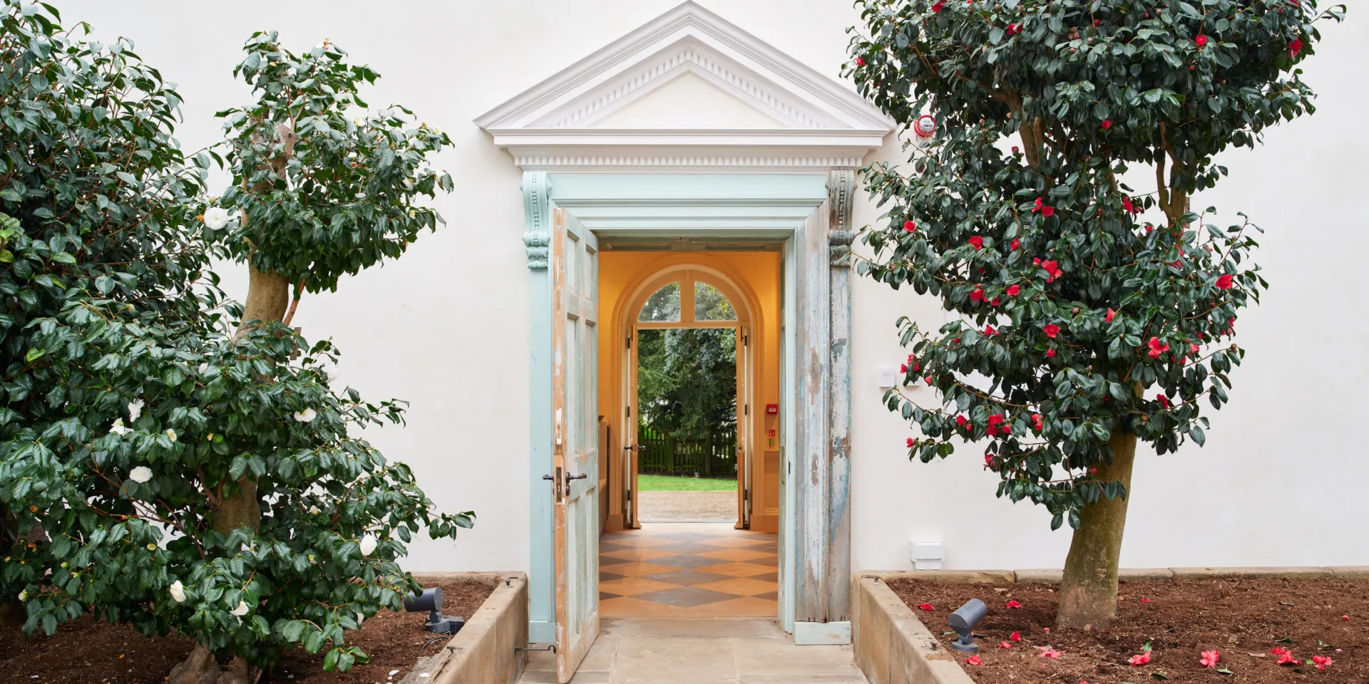 A doorway with a pediment with trees on either side
