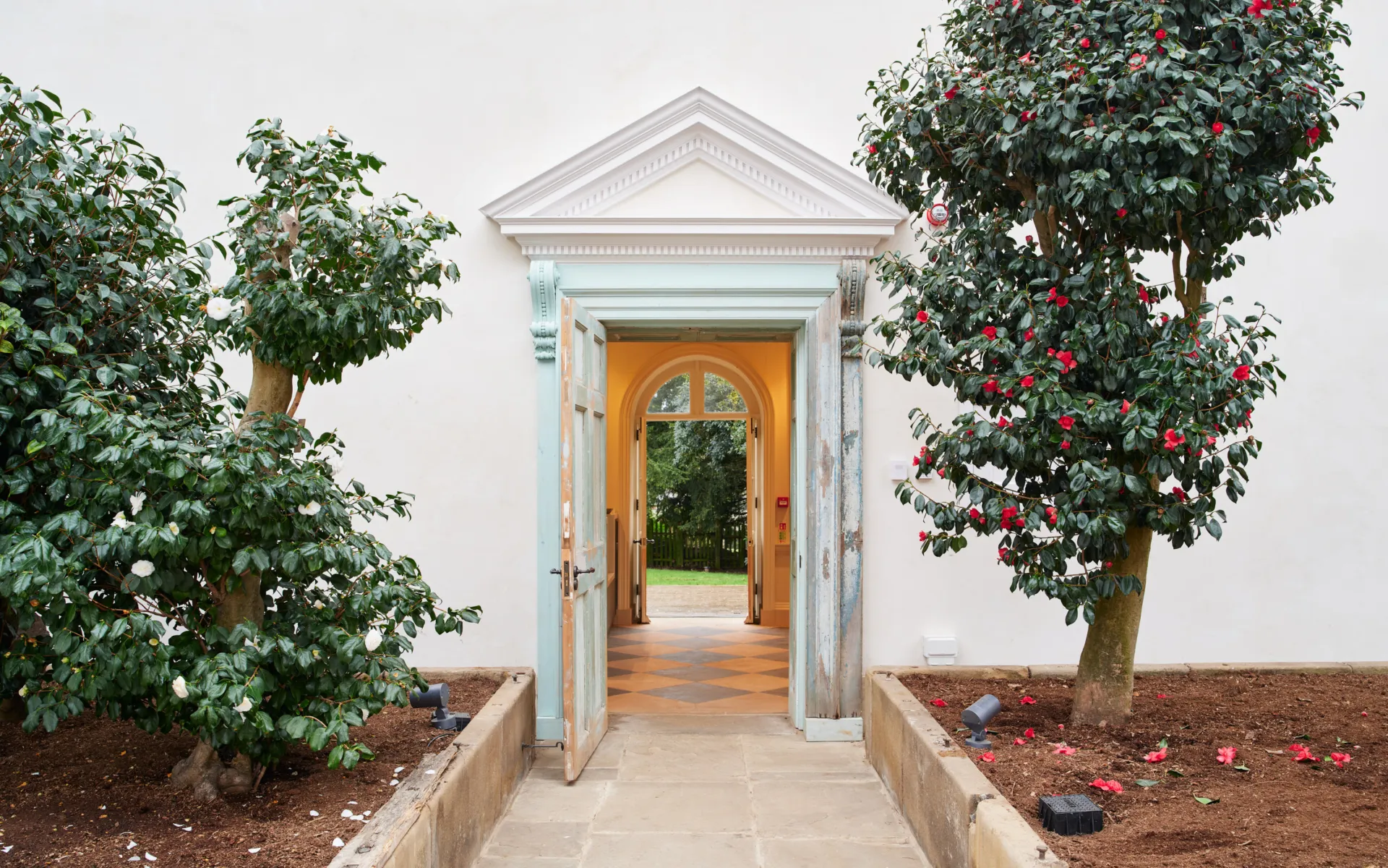 A doorway with a pediment with trees on either side
