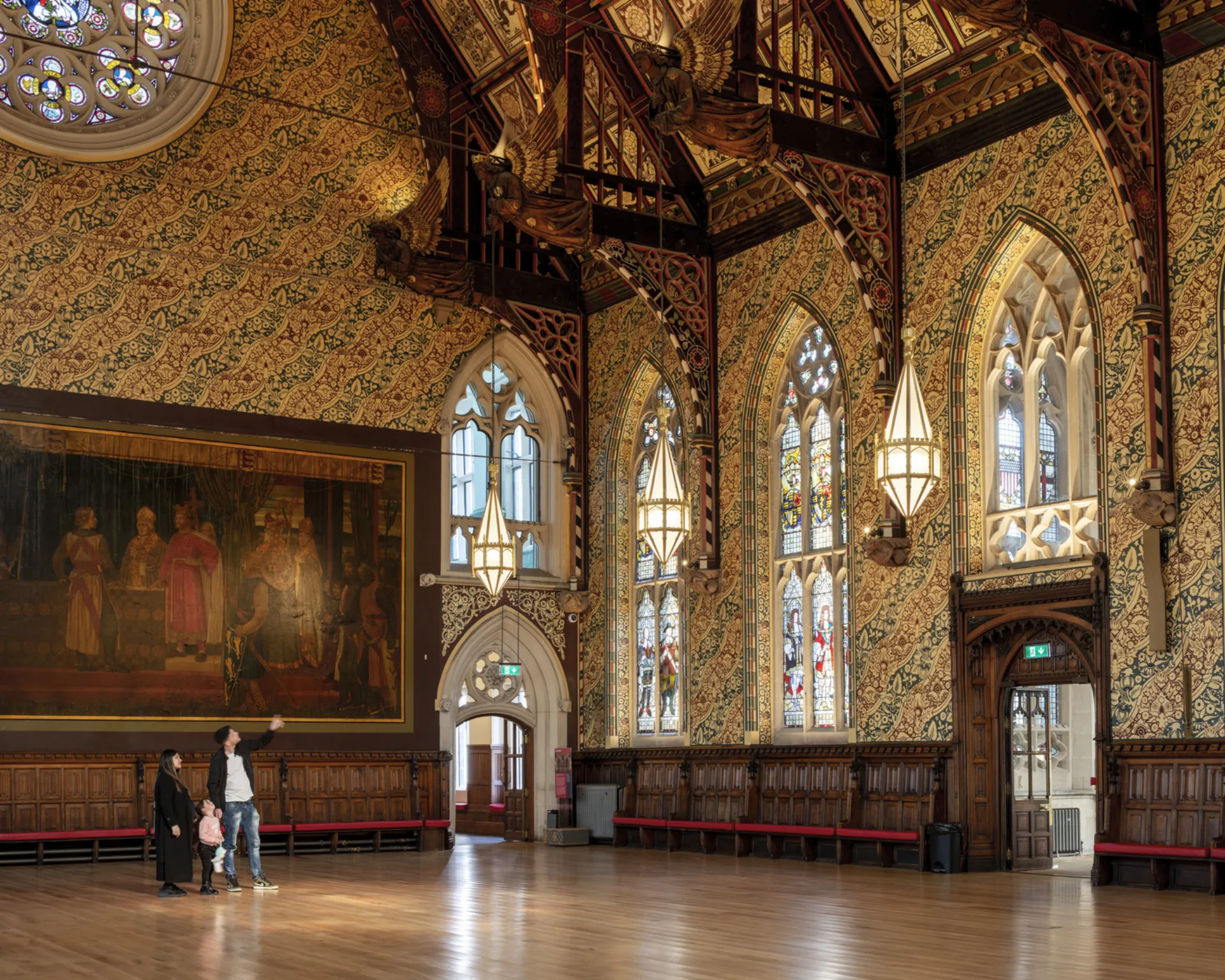 People in a gothic hall looking at the stained glass windows