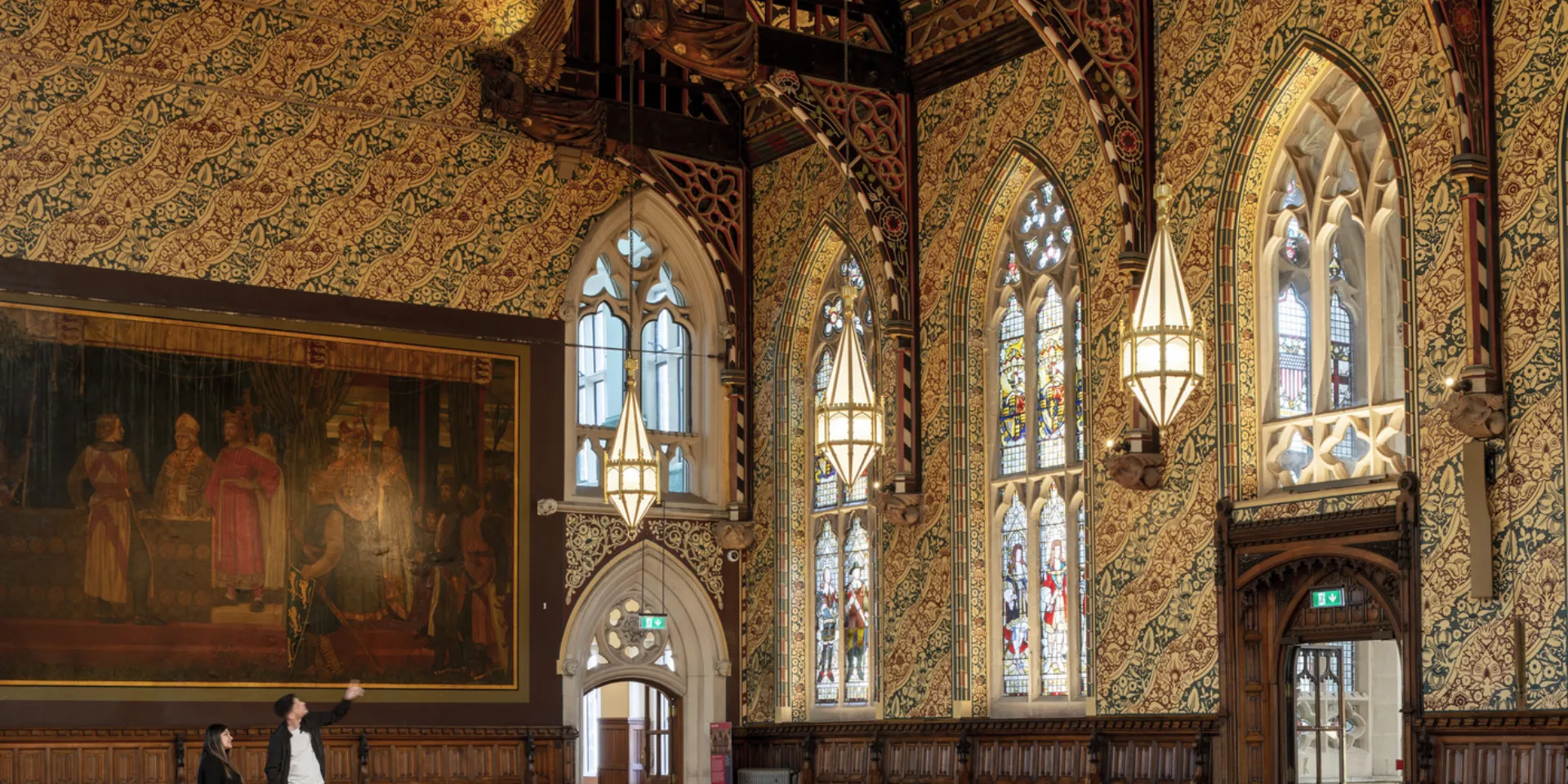 People in a gothic hall looking at the stained glass windows