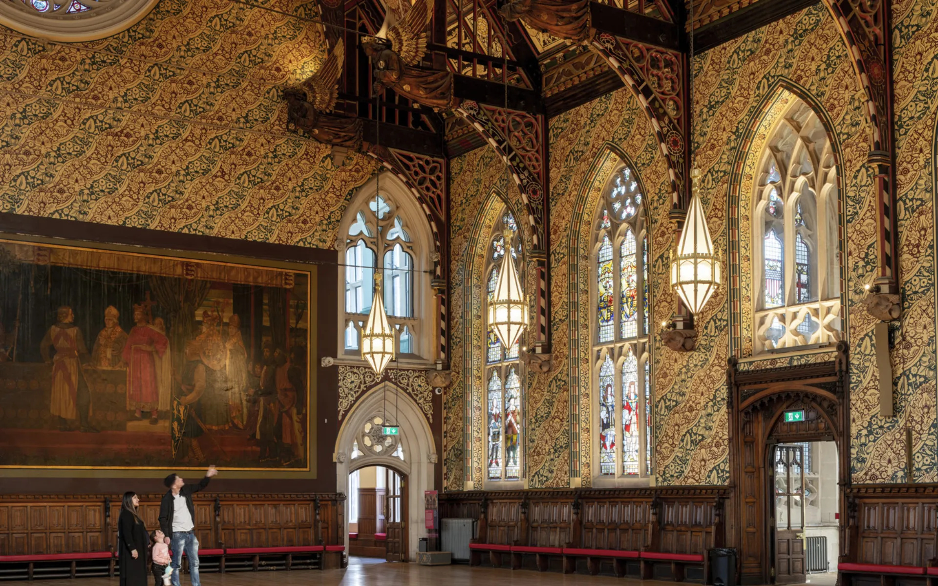 People in a gothic hall looking at the stained glass windows