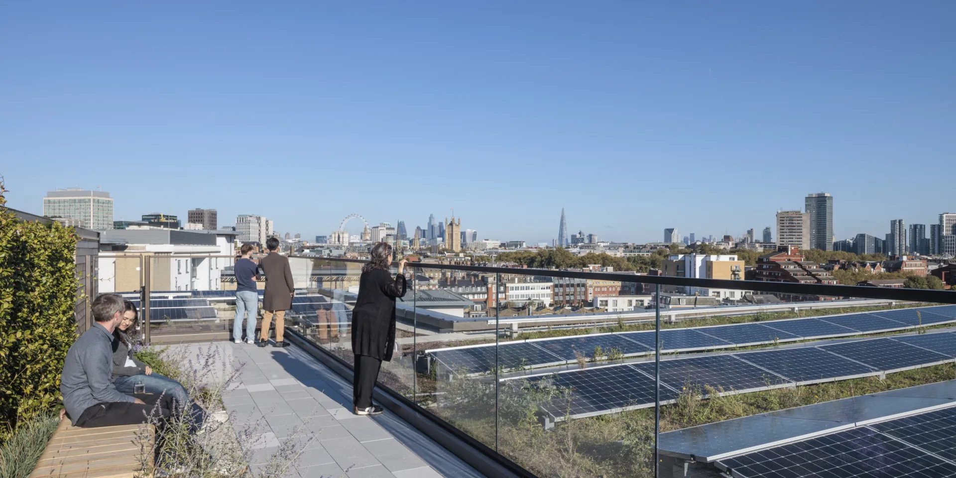 People sitting on the roof top of the new building, overlooking rows of PV panels
