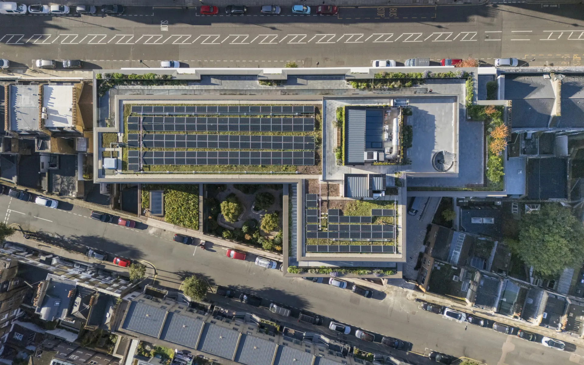 aerial shot of a building, seeing PV panels and greens on the roof
