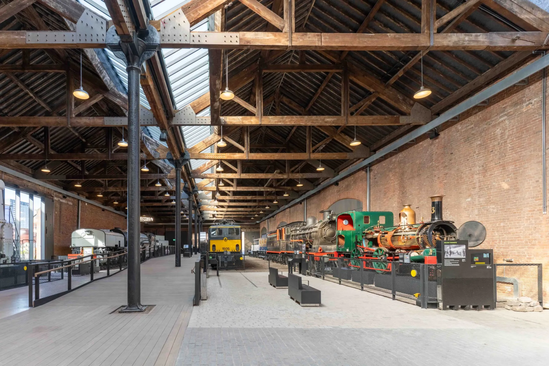 A view of the inside of the Power Hall, showing the train engine exhibits on the right of the image, with seating.