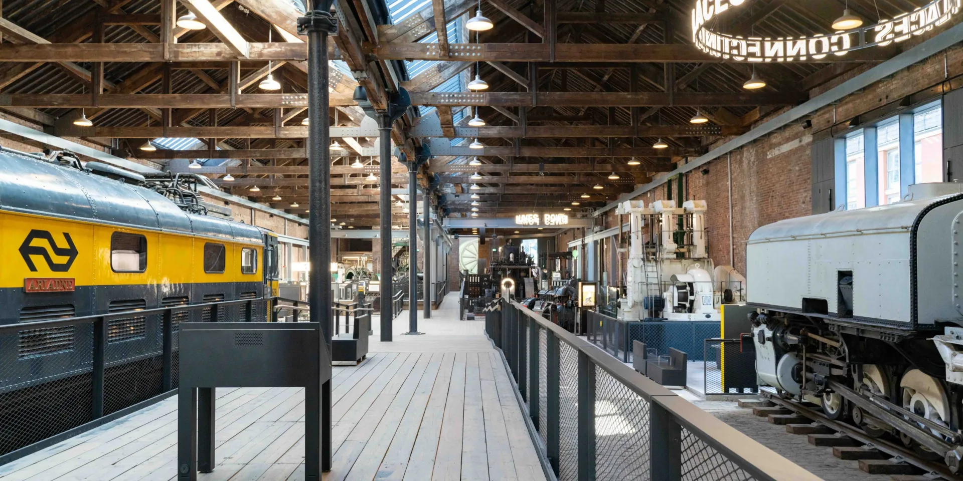 A brightly lit view inside the Power Hall, showing a diesel locomotive and smaller, static industrial machines.