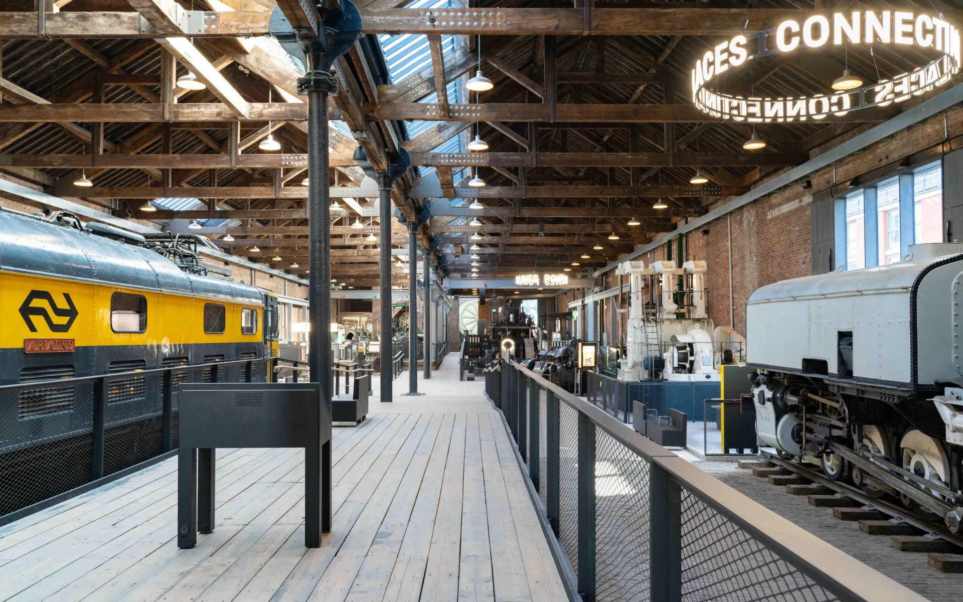 A brightly lit view inside the Power Hall, showing a diesel locomotive and smaller, static industrial machines.