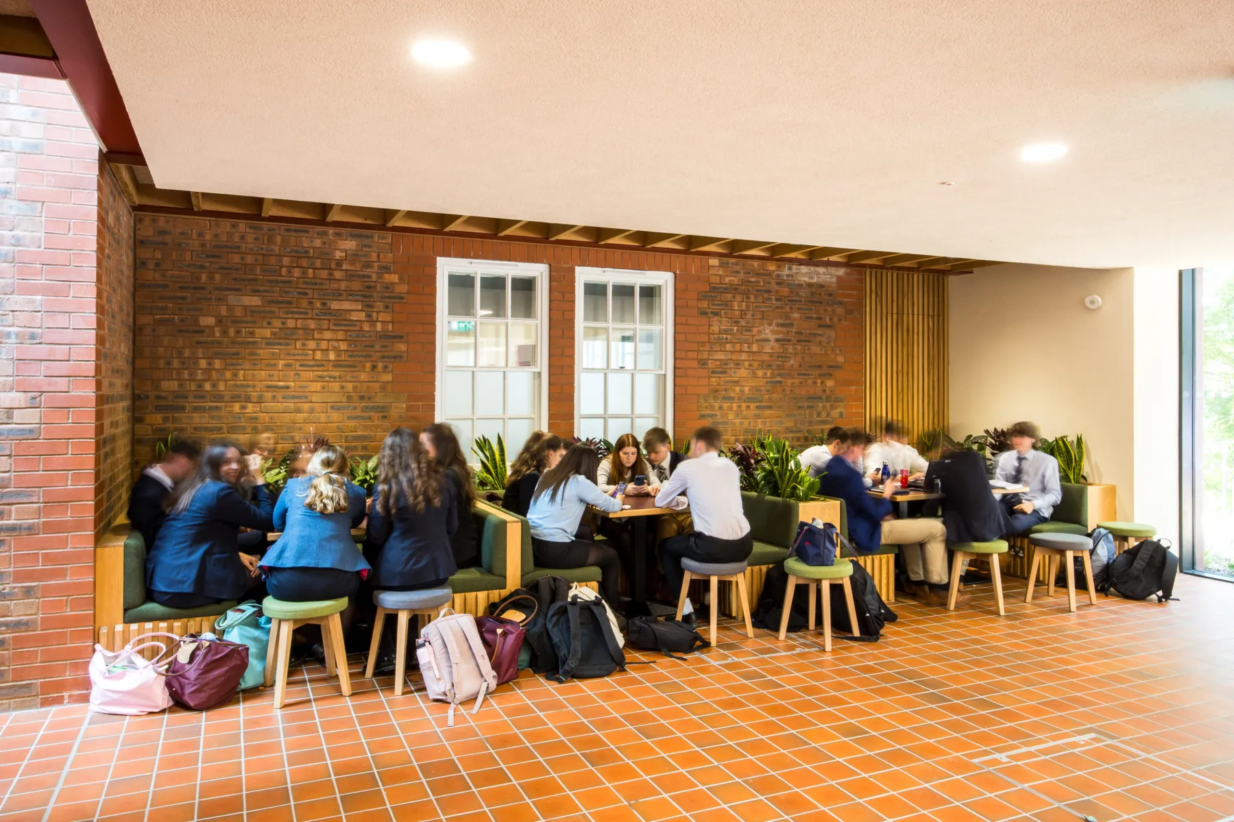 Brick-lined seating area with students gathered around tables and integrated planters.