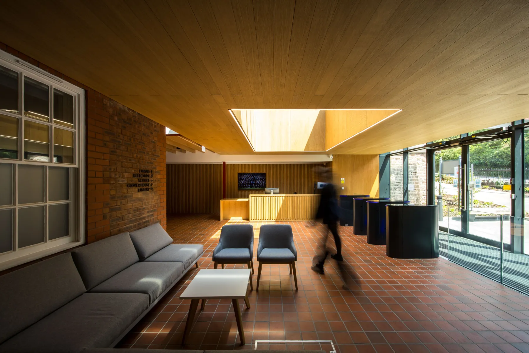 Reception area with seating, timber finishes, and a desk near the main entrance.