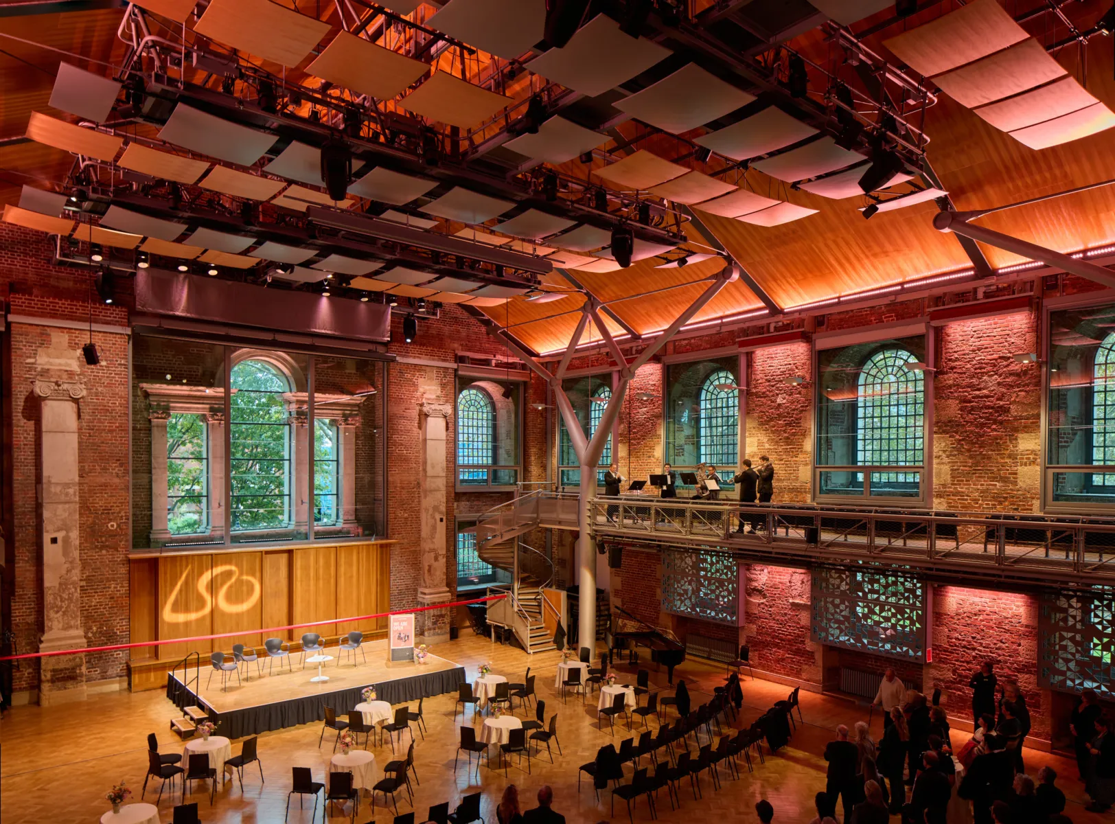 Large performance hall with stage, audience seating, and musicians playing on an upper gallery.