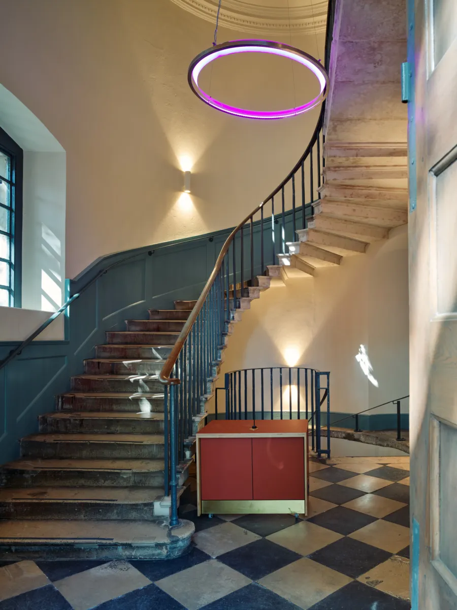 Curved staircase with stone steps and a circular pendant light in a bright interior.