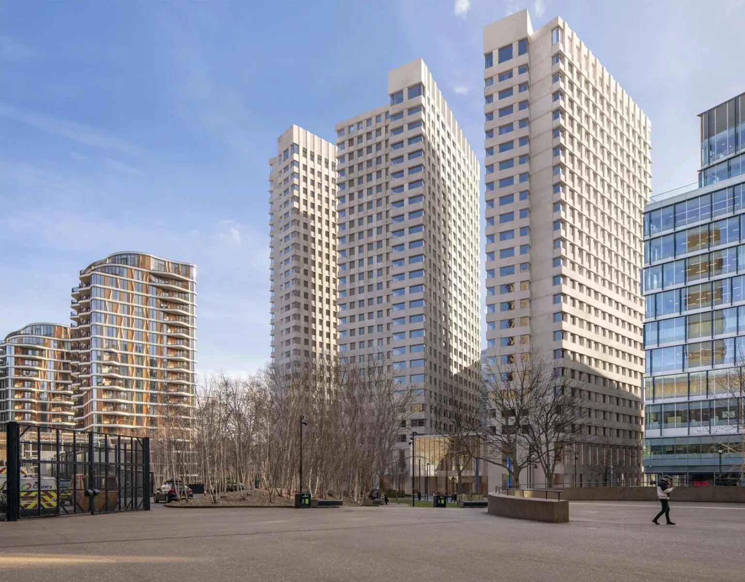 Image shows a blue sky with three modern residential towers