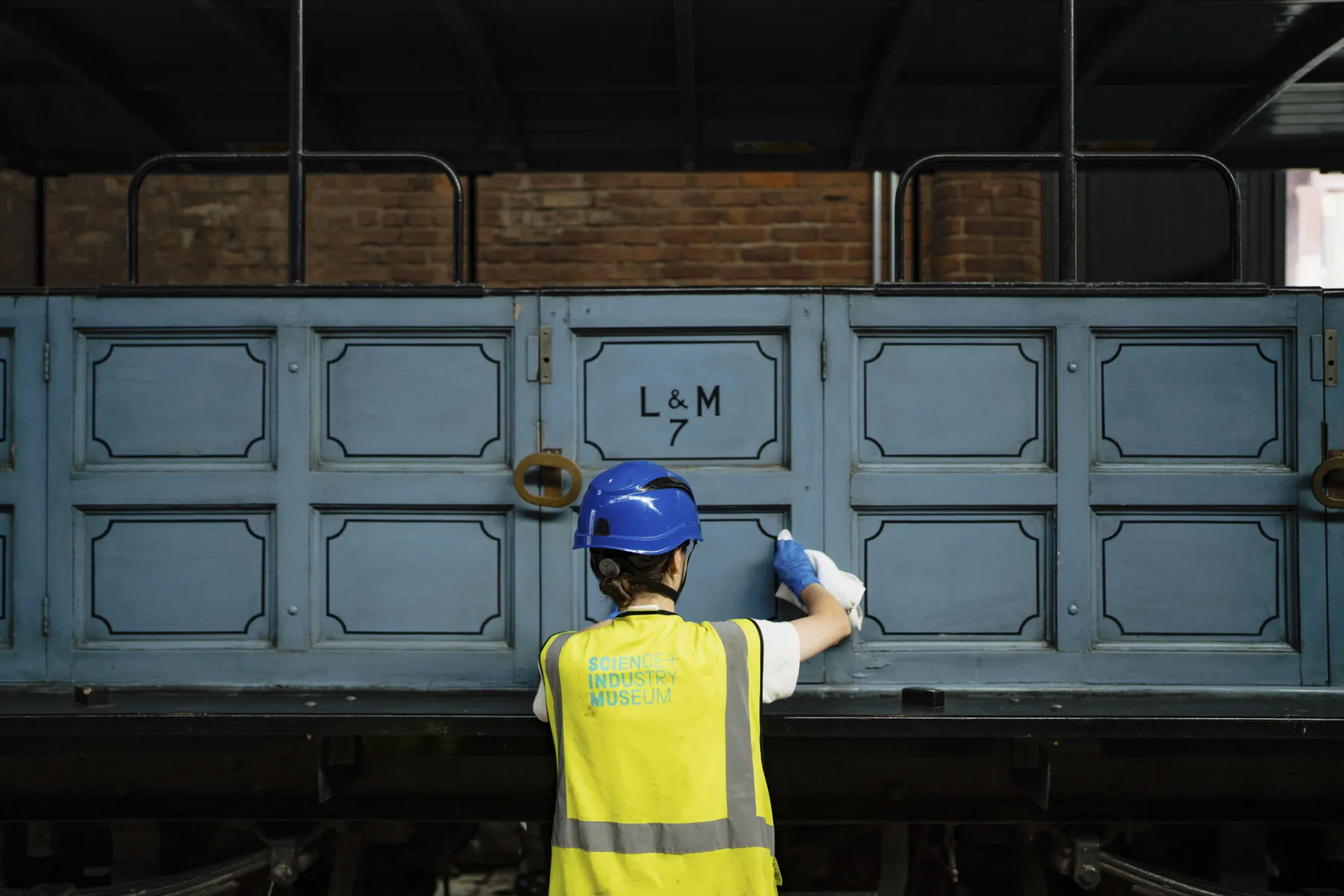 Person cleaning the side of a blue train carriage