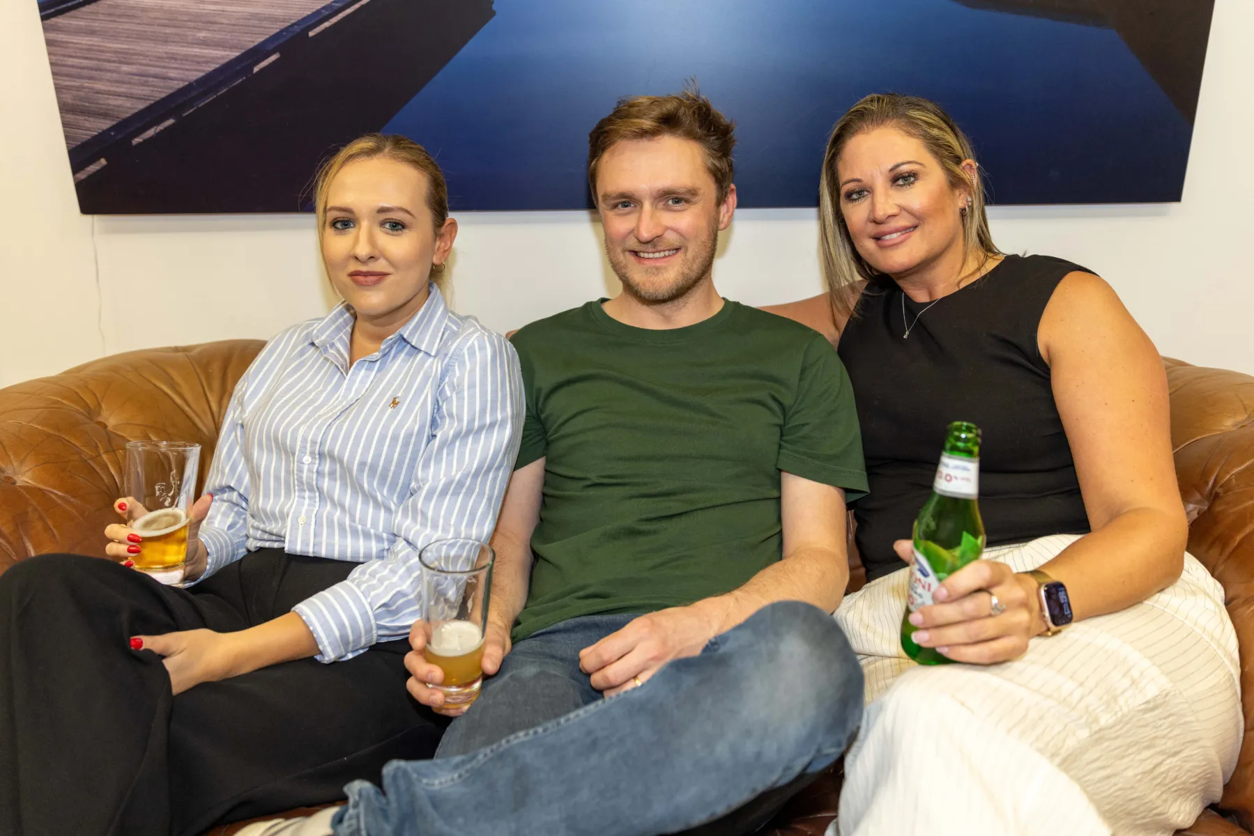 Three people sat drinking beers on a sofa in the Manchester office kitchen