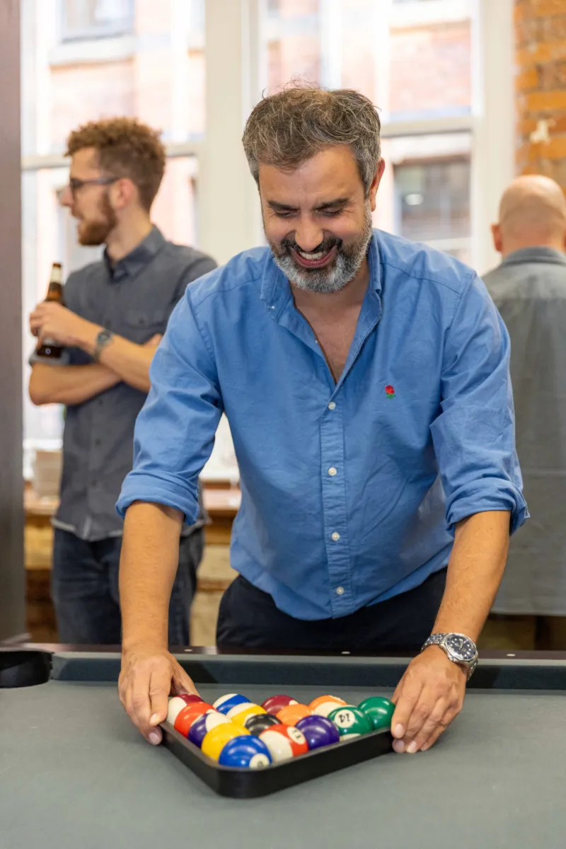 Man in a blue shirt setting up the balls for a game of pool