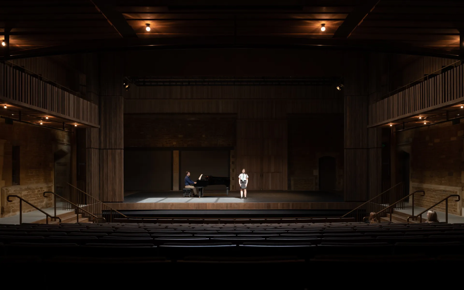 Photograph of young performer on stage at Nevill Holt Opera, accompanied by a pianist.