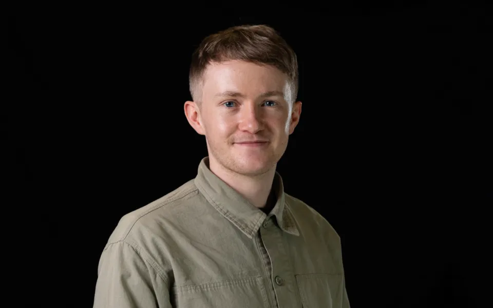 A headshot of Jake Kay wearing an olive green shirt