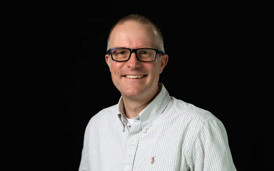 A headshot of Mark Gorin wearing glasses and a white shirt