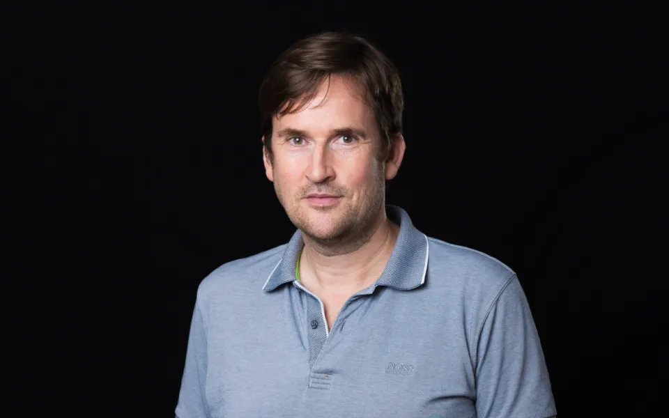 A headshot of Nick Cramp wearing a blue polo shirt