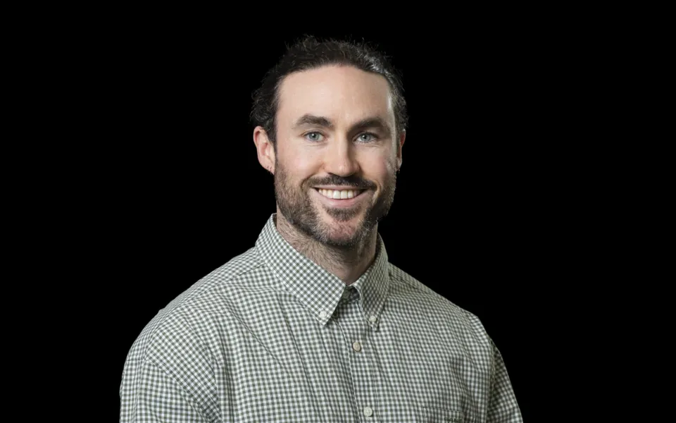 A headshot of Jack Hayhurst wearing a green and white checkered shirt