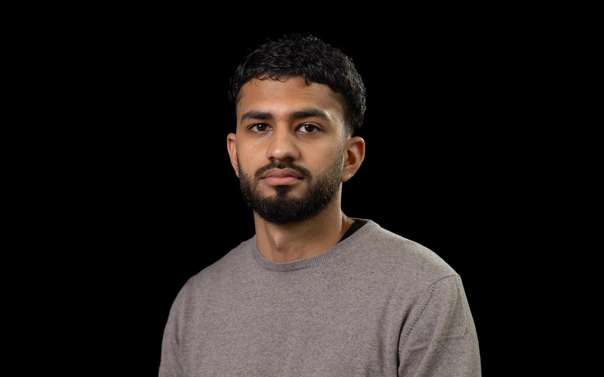 Head and shoulders portrait of Asad in a grey jumper.