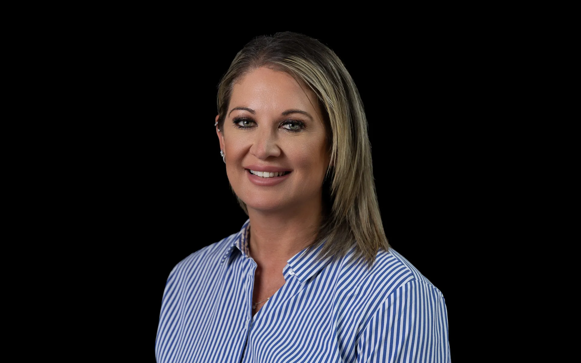 Portrait photo of Emma smiling, and wearing a blue and white striped shirt.