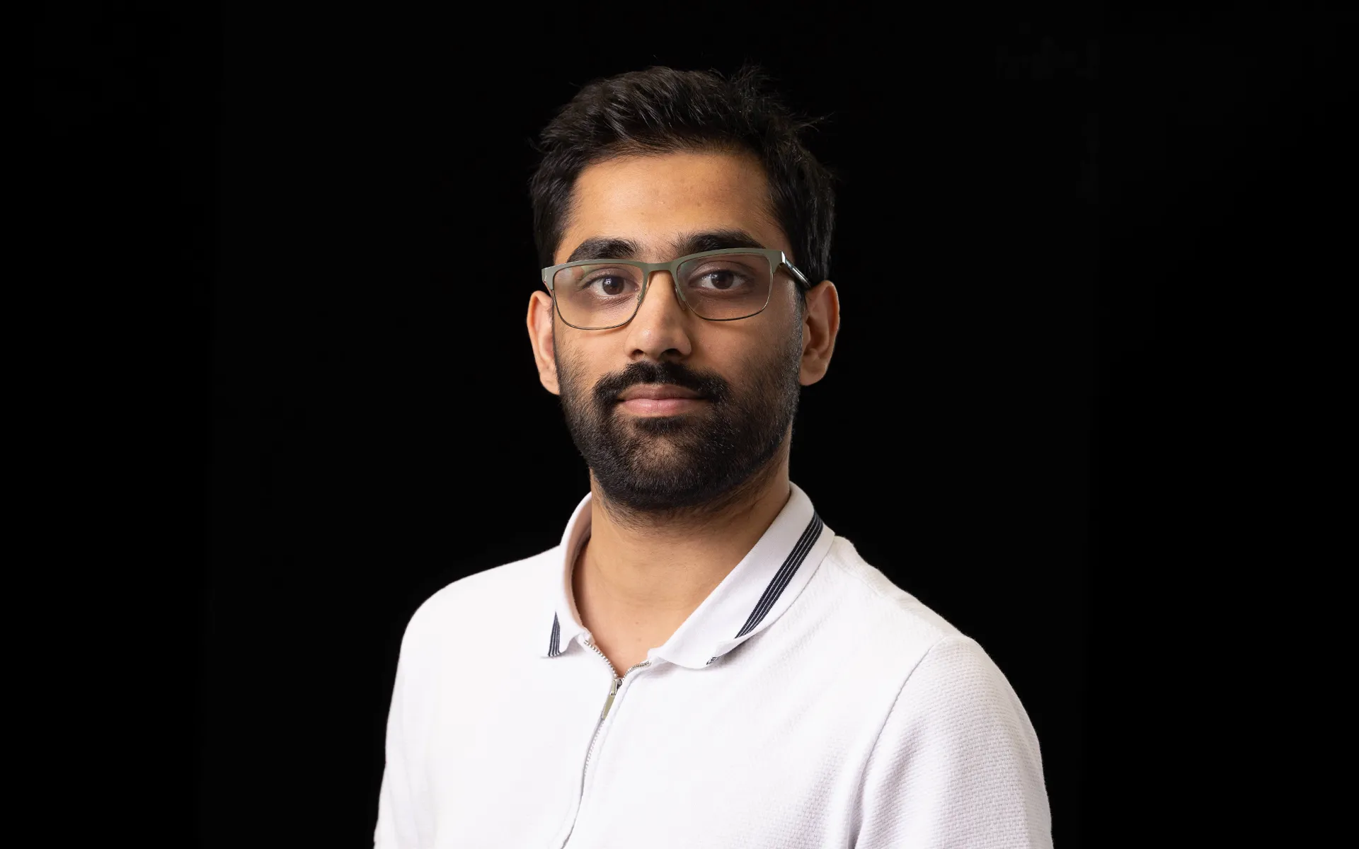 A portrait of Abdur Raheem Ali wearing a white shirt against a black background.