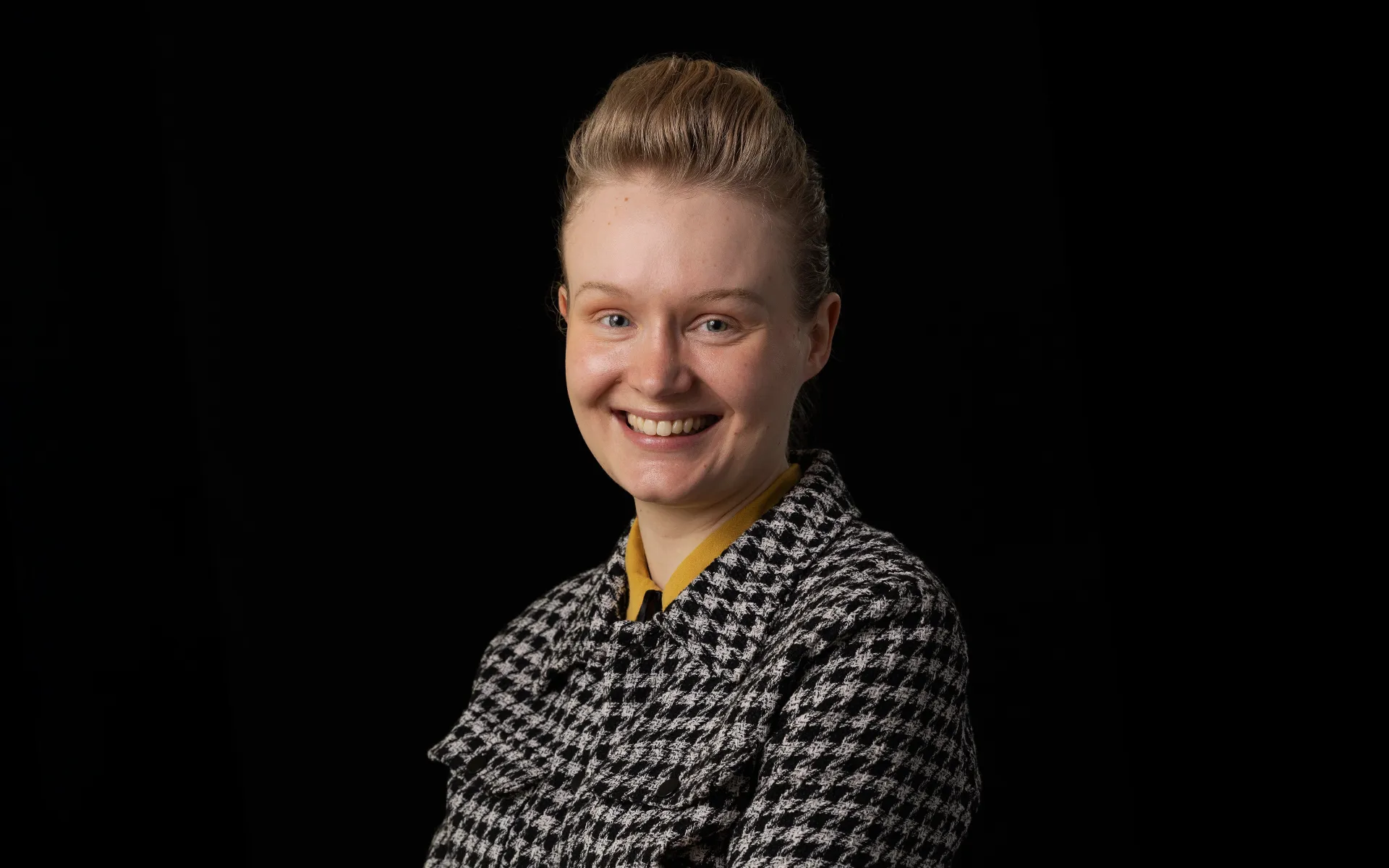Portrait of Brooke Smith wearing a checked shirt against a black background.