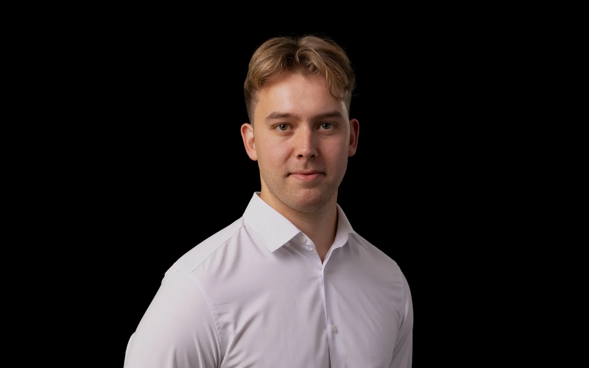 Portrait of Ewan Mears wearing a white shirt against a black background.