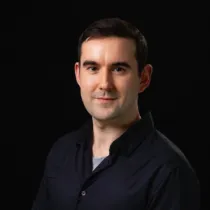 A headshot of Alexander Campbell wearing a black shirt