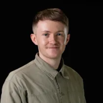 A headshot of Jake Kay wearing an olive green shirt