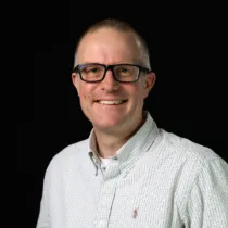 A headshot of Mark Gorin wearing glasses and a white shirt