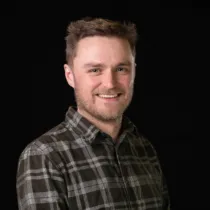 A headshot of Chris Flannery wearing a dark grey checkered shirt