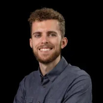 Photo of Tom in a grey-blue shirt, smiling at the camera
