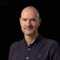Portrait of Brian Moore wearing a dark shirt against a black background.